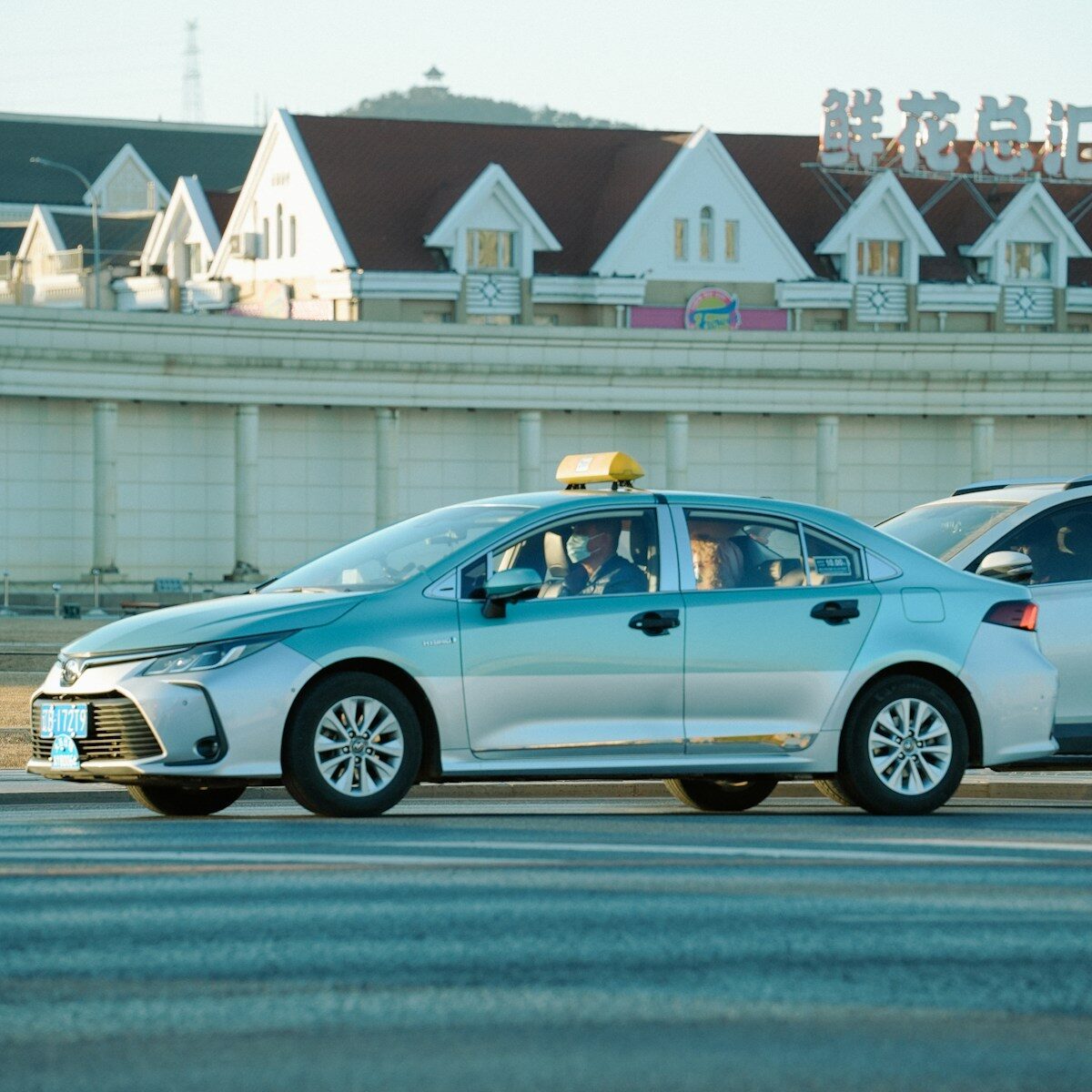 A silver taxi driving on a street.